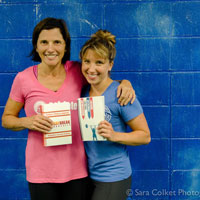 Custom fitness journals can help motivate you as you track your success and checkoff your fitness goals from the new year. Two women with their workout journal